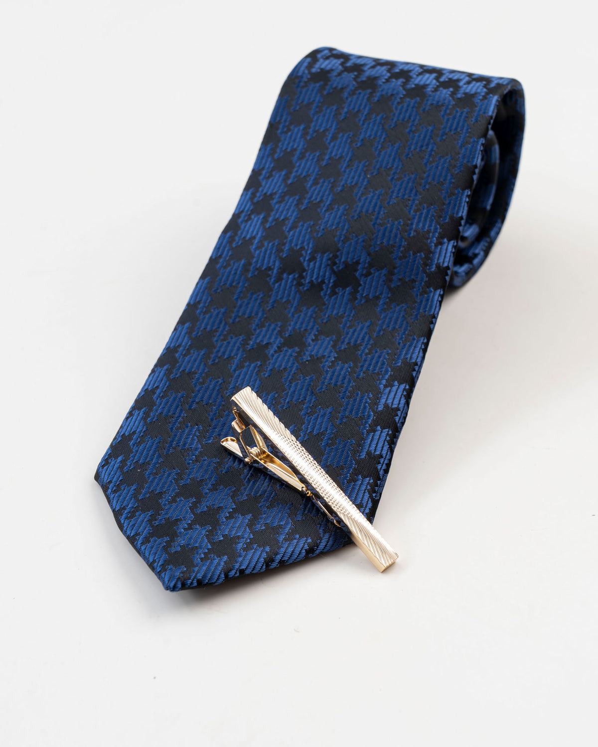 Gold-tone tie clip attached to blue textured tie