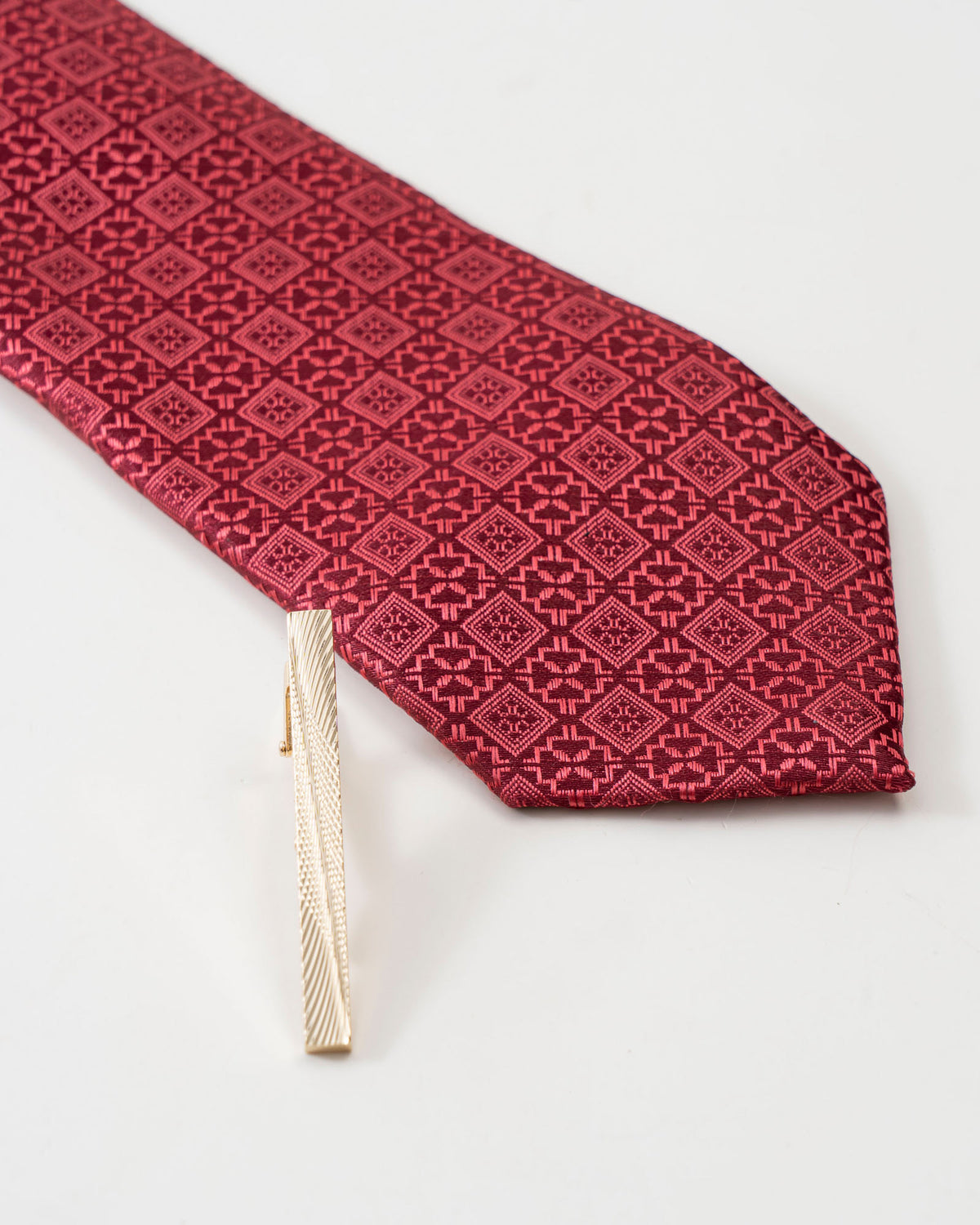 Gold-tone tie clip attached to a patterned formal tie