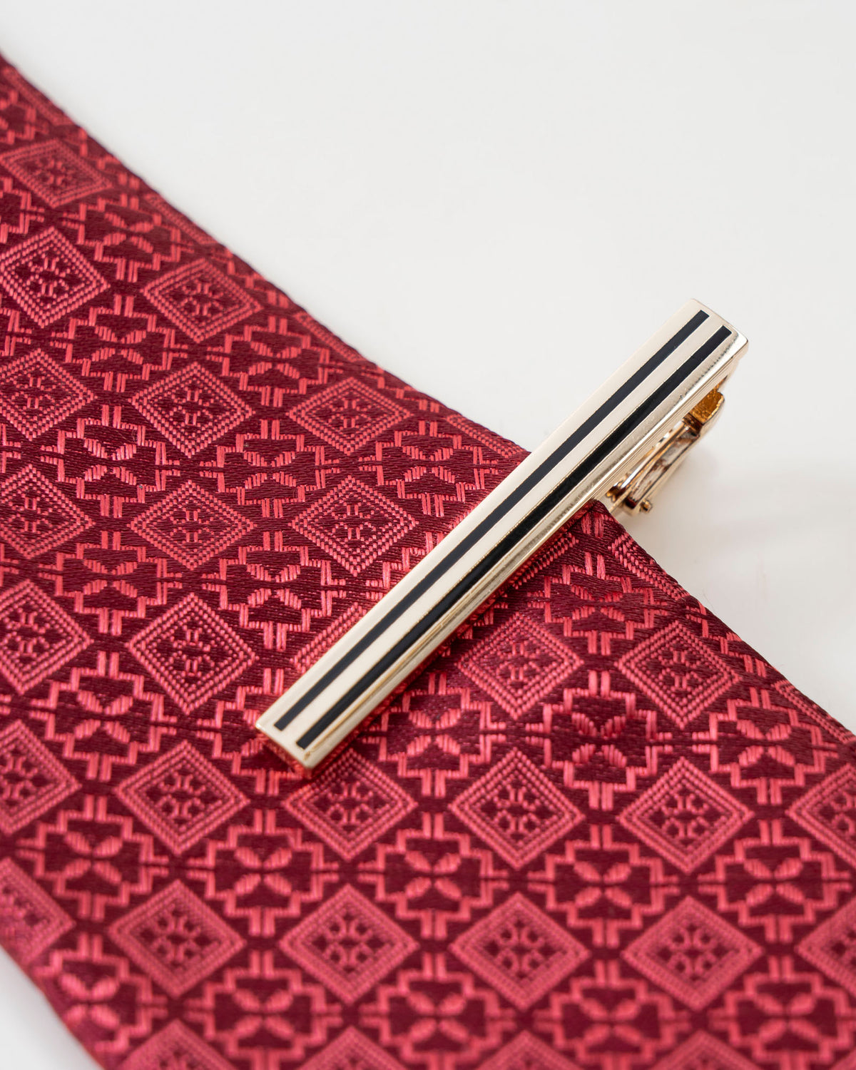 Black stripe gold-tone tie clip shown with a patterned tie