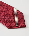 Striped gold-tone tie clip attached to a formal tie