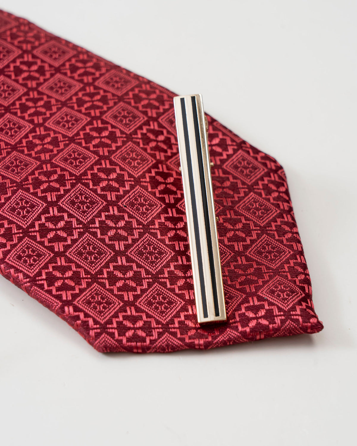 Striped gold-tone tie clip attached to a formal tie