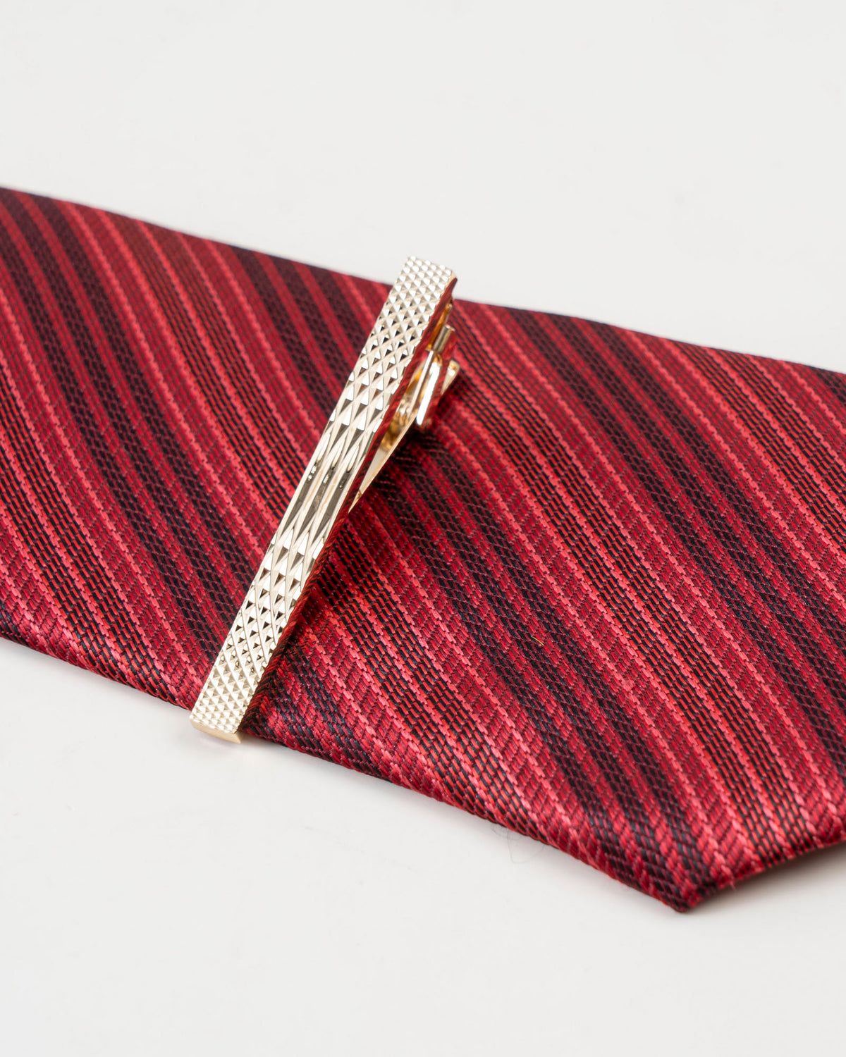 Diamond-textured tie clip attached to a patterned formal tie