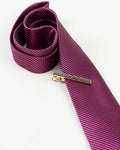 Gold-tone tie clip with black stripes styled on a formal tie