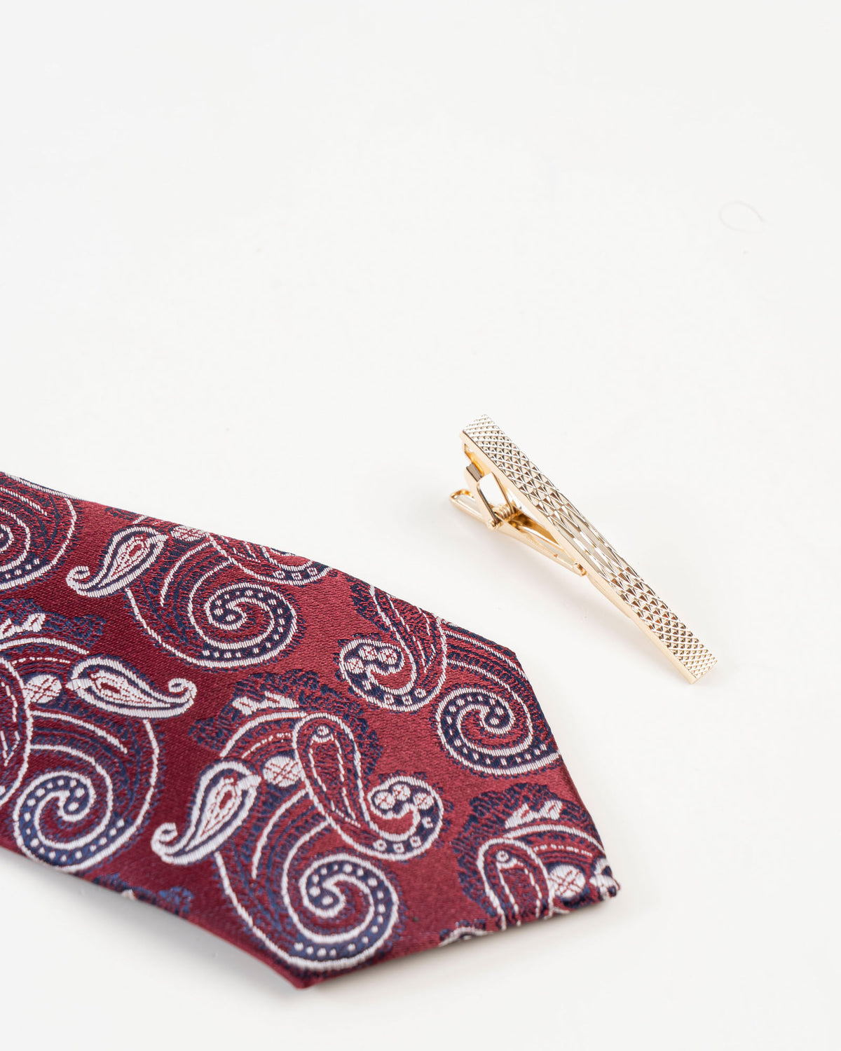 Gold-tone textured tie clip styled with a burgundy patterned tie