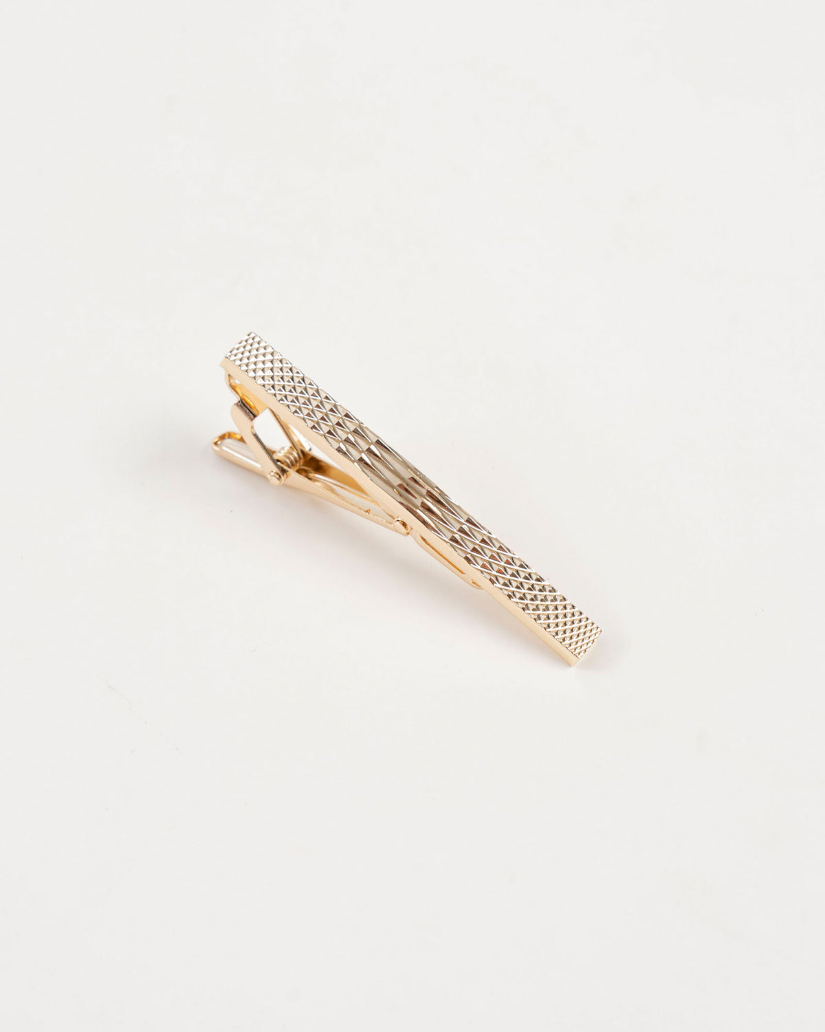 Gold-tone tie clip beside a burgundy paisley tie