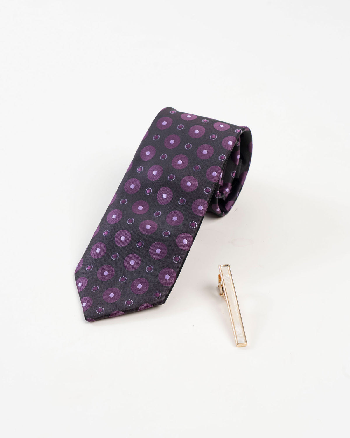 Classic gold-tone tie clip shown with a black and purple dotted tie