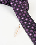 Classic gold-tone tie clip shown with a patterned formal tie