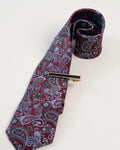 Gold-tone tie clip with black center detail styled on a paisley tie