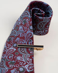 Gold-tone tie clip with black detail paired with a burgundy paisley tie
