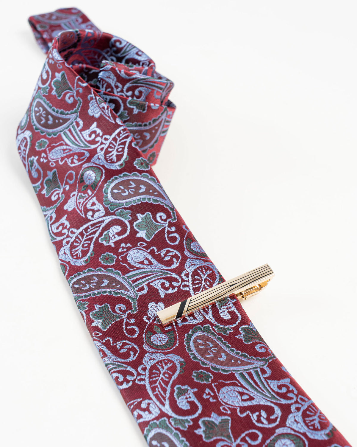 Black line gold-tone tie clip shown with a burgundy paisley tie
